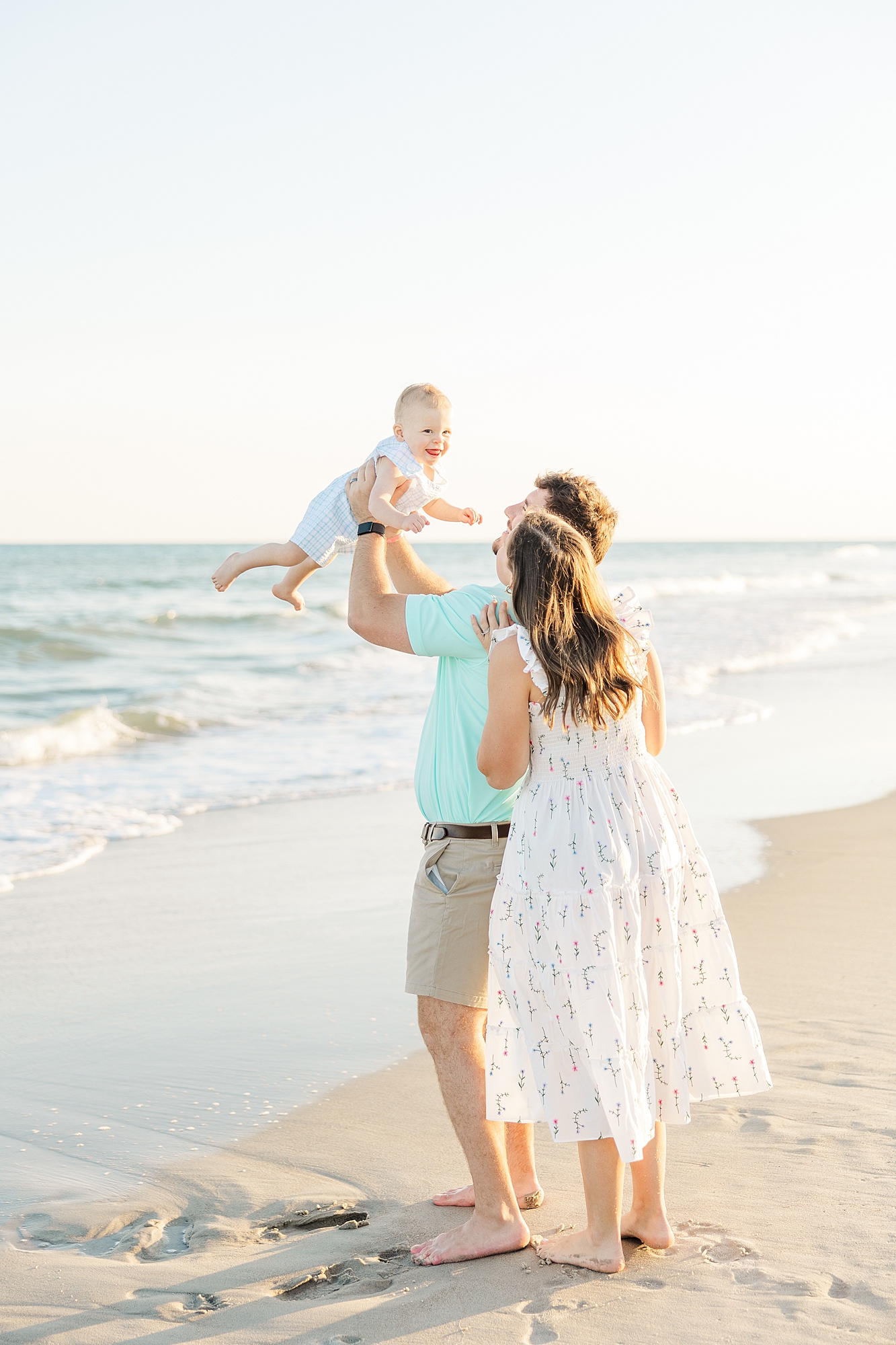 emerald isle beach photographer parents holding baby on beach