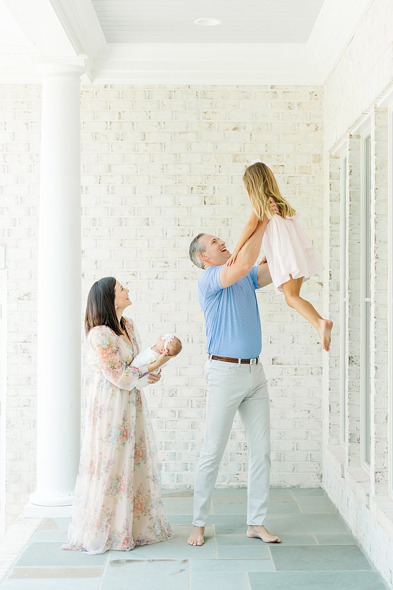 Greenville NC Newborn photographer toddler in newborn photo being thrown in the air by dad with mom and baby girl watching