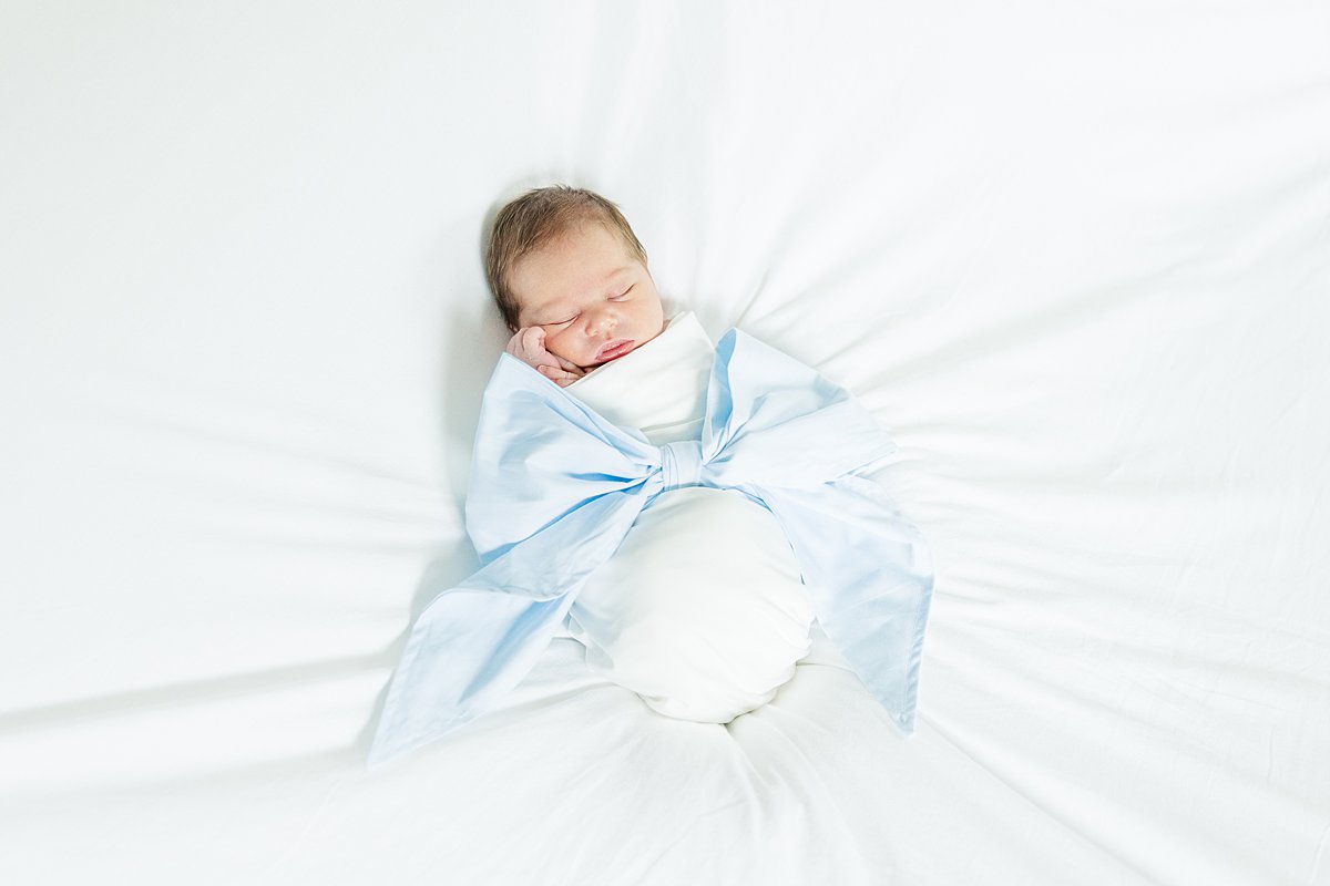 newborn baby boy in bow swaddle on bed birth story Greenville NC newborn photographer