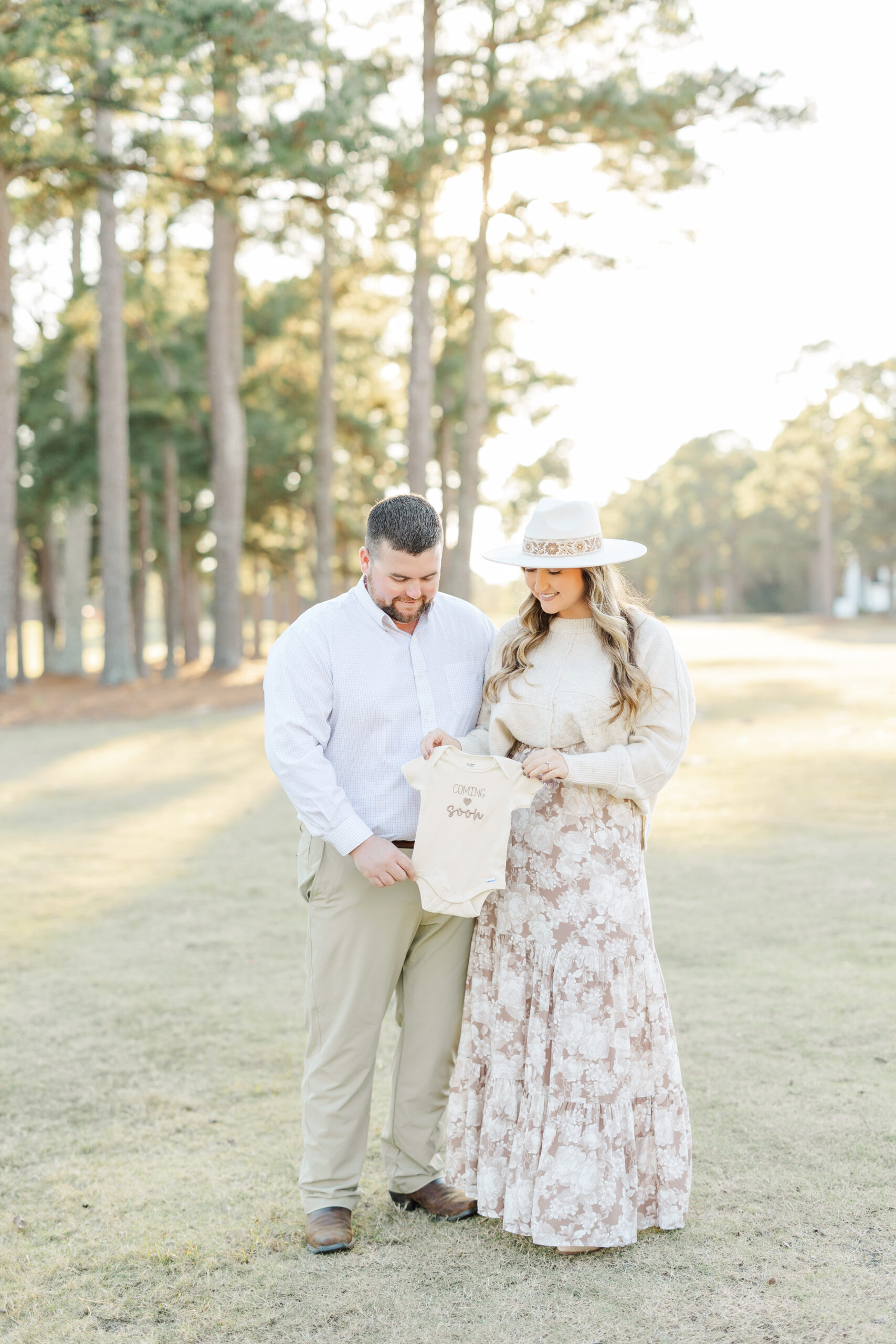 pregnancy announcement with parents holding a baby onesie outfit